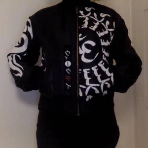  - En reversable svart bomber jacka med print. 