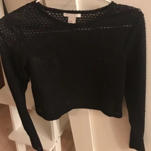  - Cropped top med lång ärm, svart och lite transparent hålmönstrad, från h&m trend  Storlek 34 Mycket fint skick. Använts 2 ggr 