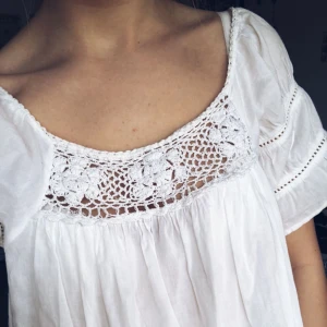  - Vit blus med virkade detaljer. Vet inte var den är ifrån eller vilken storlek, jag brukar ha XS men den skulle utan tvekan passa minst en M med. Skulle tro att denna är st. 36. Köparen betalar frakt.