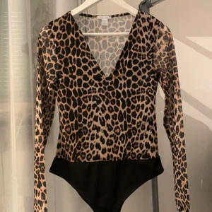 Leopardmönstrad body med mesharmar med v-ringning.  - Leopardmönstrad body som funkar till vardags men även fest/finare tillställning. Aldrig använd och köpt på New Yorker. Ärmarna är i mesh/genomskinlig och v-ringning. Väldigt stretshig och bekvämt och luftigt tyg. 