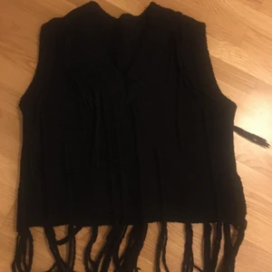 Trendig svart v ringad väst med fransar  - Säljer min snygga svarta v-ringad väst, knappt använd så i väldigt bra skick. Super trendigt plagg just nu som passar med allt 💥