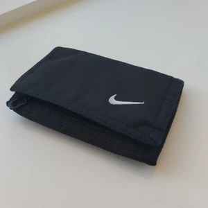 Nike plånbok - Snygg plånbok från nike som jag ej använder längre. Har många bra fack. Är 13x9 cm när den är stängd. 
