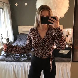 omlotttröja i leopardmönster  - En omlottröja i leopardmönster som har utsvängda armar. Köpt på NAKD o är använd 1-2 gånger. storlek S men skulle säga att den passar alla från XS-M då man skjysterar hur tajt den ska sitta. 