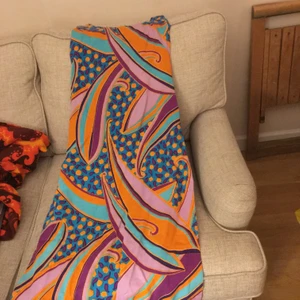 Karamellig klänning - Långklänning i fina färger med två höga slitsar på sidorna. Bra skick fast sömmen har släppt en aning på ena sidans slits. Troligen 70-tal och hemsydd. Tjockare bomull som är lite ribbad. Frakt tillkommer. 