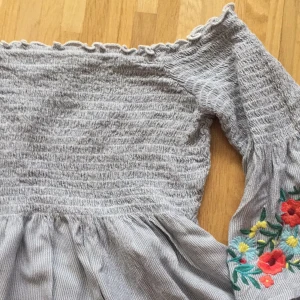 broderad topp - jättesöt broderad off shoulder från hollister. strl S och endast använd 1 gång. HÖR AV ER VID FRÅGOR!först till kvarn och om fler vill ha blir det budgivning :)