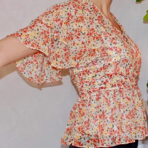 Blommig Blus Med Fjärilsärmar Zara - Blommig söt blus i glada färger! Fjärilsärmar och veckat tyg vid midjan. Dold dragkedja i sidan, tunt fint tyg. Ej stretch. Endast använd två gånger, fint skick! Den har fastsydda små korsande band över urringningen. Frakt tillkommer, 44kr☀️
