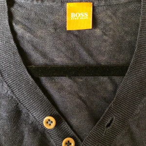 Boss tunnstickad tröja i marinblått L - Tunnstickad tröja med fina detaljer från Boss Hugo Boss i Stl L (passar även M). Klassisk tröja som med sitt tunna tyg gör sig utmärkt i vår och sommar.