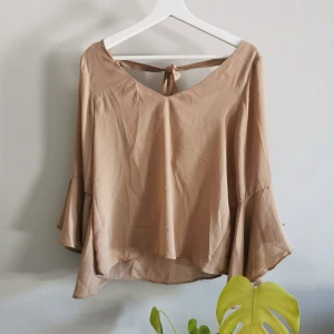 Blus från NA-KD - Fin blus från NA-KD, knytband i bak, volang ärmar. I princip oanvänd. Köparen står för frakt. 