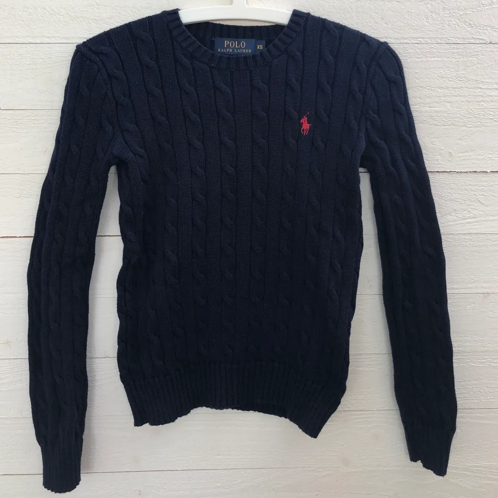 Marinblå kabelstickad tröja med rött märke från Ralph Lauren i strl XS. Köparen står för frakt. . Tröjor & Koftor.
