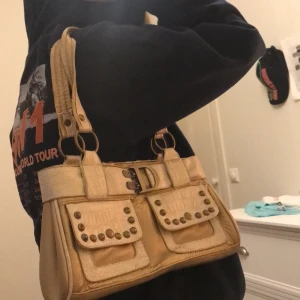 Guldig handväska - Jätte fin guldig handväska. Köpt second hand och är i bra skick förutom banden som syns på andra bilden men det är inget man märker när den är på