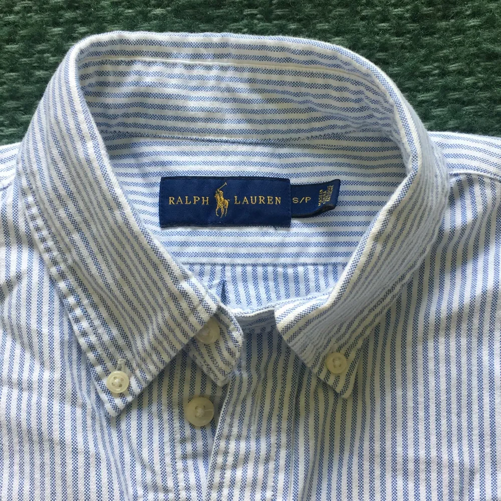 En klassisk ljusblå och vitrandiga Ralph lauren skjort, något figursydd. Storleken small petit. Knappt använd! Säljer för 150kr + frakt! . Blusar.