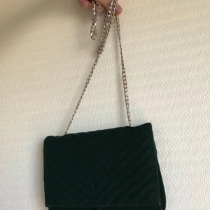  - Axelväska i en mörkgrön färg med silvriga detaljer. Använd en gång. 