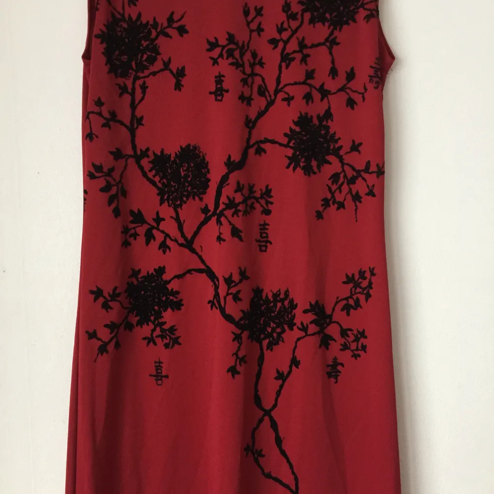 Mörkröd ärmlös tajt långklänning i asiatisk stil. Vackert asiatiskt blommönster. Klänningen kommer från Impuls, en gång ett undernärke hos H&M. Den har aldrig använts, köptes nån gång 80-tal/-år 2000. . Klänningar.