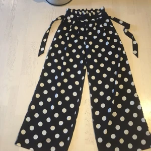  - Mörkblåa byxor med vita prickar.  Använda 1 gång. Ens knäppet lite löst men går enkelt att lösa med ett egen gjort stygn. Samma avslappnade passform som byxor från weekday