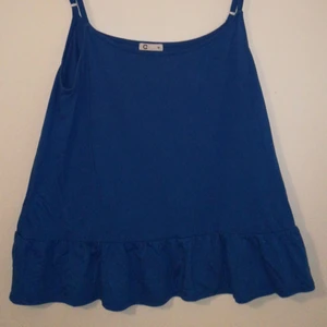  - Blus /linne I klarblå färg med volang nedtill   Tunna justerbara axelband Frakt betalas av köparen 
