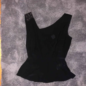  - Svart ”festlinne” som går omlott. Djup i ryggen med glitterdetaljer på ena axeln!