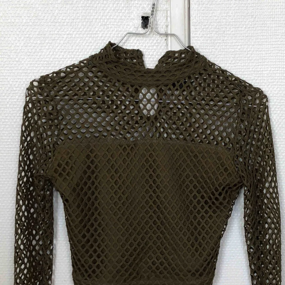 Mesh material, tight, with a slight turtleneck vibe, the arms are well fitted, crop top. . Toppar.