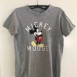  - En grå T-shirt med Mickey Mouse på, T-shirten är sparsamt använd, utan fläckar eller andra tecken på användning. Säljer den för att den tyvärr inte används lika mycket som den borde. 