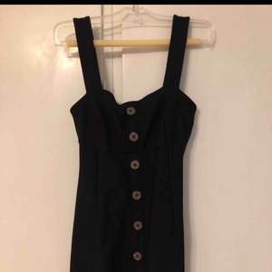 Svart klänning med knappar i lyxigt material från Urban Outfitters  Stl XS/S