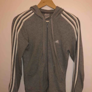  - En klassisk adidas hoddie med blixtlås. Fint skick förutom en liten fläck på ena armen.