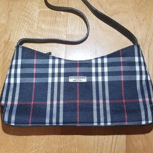 Burberry axelväska - Säljer min äkta burberry axelväska som tyvärr inte kommit till använding. Trendig och passar bra inför hösten. Man får plats med det mesta (nyklar, mobil etc). Den är i gott skick (använt 2 gånger). Skriv privat vad du budar så lägger jag in det här!💜