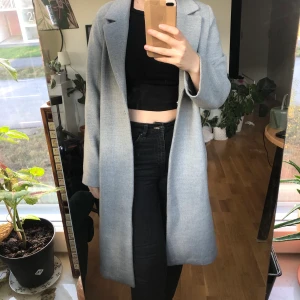 Grå lång kappa - Grå kappa från H&M köpt för cirka 2 år sedan. Har använt denna en del men skicket är fortfarande bra. Jag har storlek XS/S och är 164cm lång. Frakt tillkommer. 