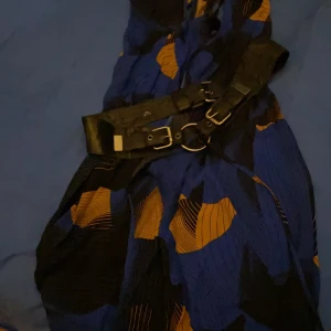 Wrap around / Klänning mönster mot elektriskt blå bakgrund - Ny ej använd Large stl men kan knytas ihop tajt. Den ska hänga över axlarna man har långärmad tajt turtleneck tröja till och tights läderbrallor och ett passande läder skärp till runt midjan. Se mina annonser shipping 66kr