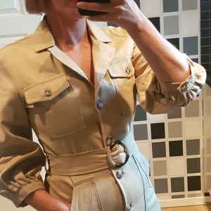 Klänning med puffärm och skärp - En hostig klänning med fin passform. Puffärm, knappar och skärp som fina detaljer.