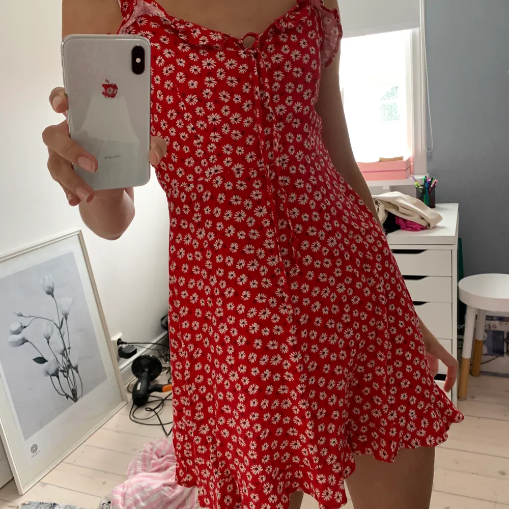 Säljer den perfekta klänningen, då den tyvärr är lite kort på mig (177cm) från pull&bear. I rött blommigt tyg och smockad i ryggen och med knytning framtill. Viker man ned den kan den  även bäras som en kjol:) . Klänningar.