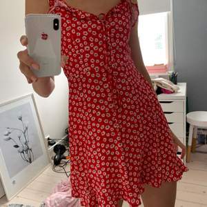 Säljer den perfekta klänningen, då den tyvärr är lite kort på mig (177cm) från pull&bear. I rött blommigt tyg och smockad i ryggen och med knytning framtill. Viker man ned den kan den  även bäras som en kjol:) 