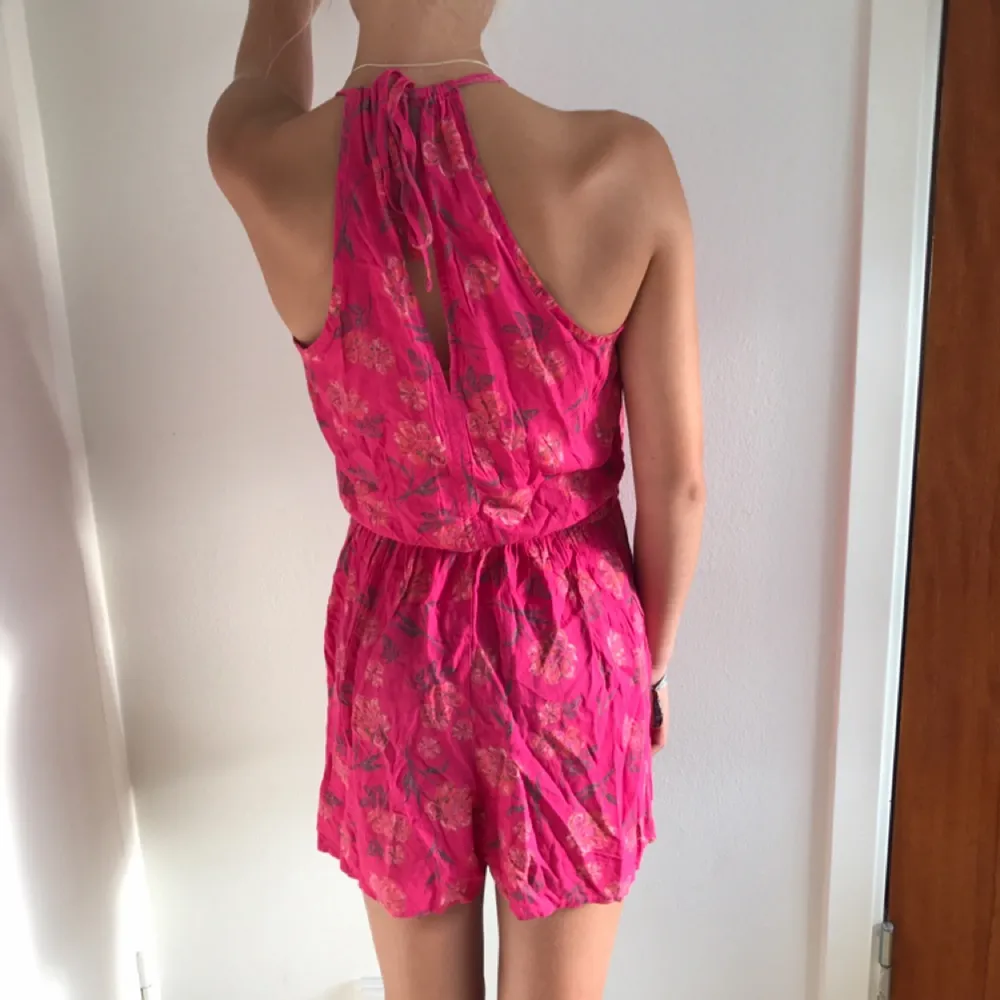 Rosa, blommig jumpsuit från Hollister i storlek XS Betalning sker via swish  Köparen betalar frakt. Klänningar.