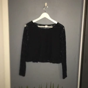  - Tröja från h&m. Svart spets med tyg under framifrån och vanlig spets på ärmarna och i ryggen. Volang  nere på tröjan. Original pris ca 150 - 200.