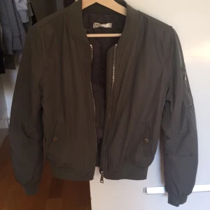  - En militärgrön bombar jacka köpt på hollies i barkaby.
