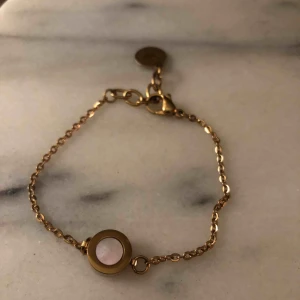  - Armband från Edbland Arctic serien i roséfärgat stål med pärlemor. Justerbar längd 16,5-19 cm. Hängets diameter är 10mm. Använd ett fåtal gånger. Kostar 299kr nytt. Tillkommer frakt.