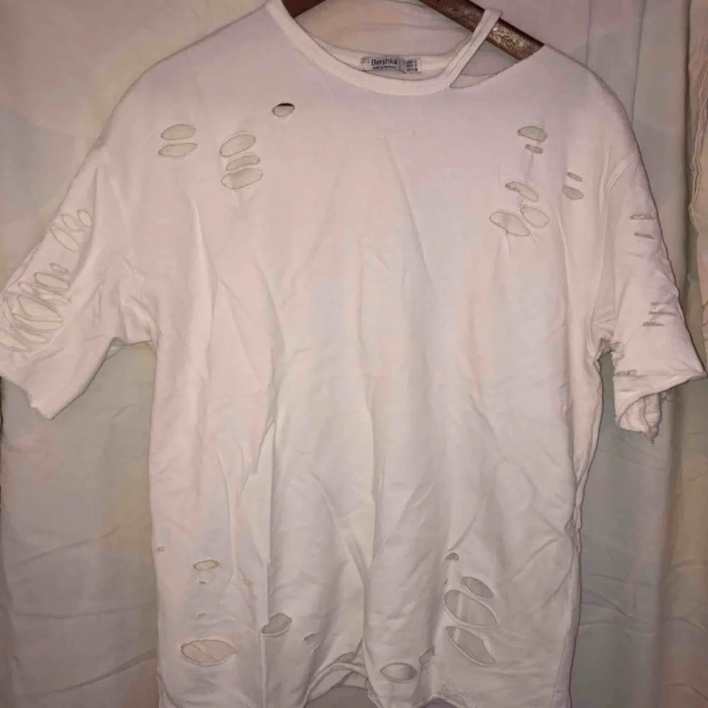 En vit oversized t-shirt från bershka med massa hål. Använd max 3 gånger. Som nyköpt. Säljs pga aldrig använd.. T-shirts.