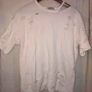 En vit oversized t-shirt från bershka med massa hål. Använd max 3 gånger. Som nyköpt. Säljs pga aldrig använd.
