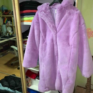  - Baby lila, knälång fejk päls kappa från Junkyard som är helt ny, inte använd alls. Frakten är oklar med tanke på vikten men det går att kolla upp vid visat intresse. 