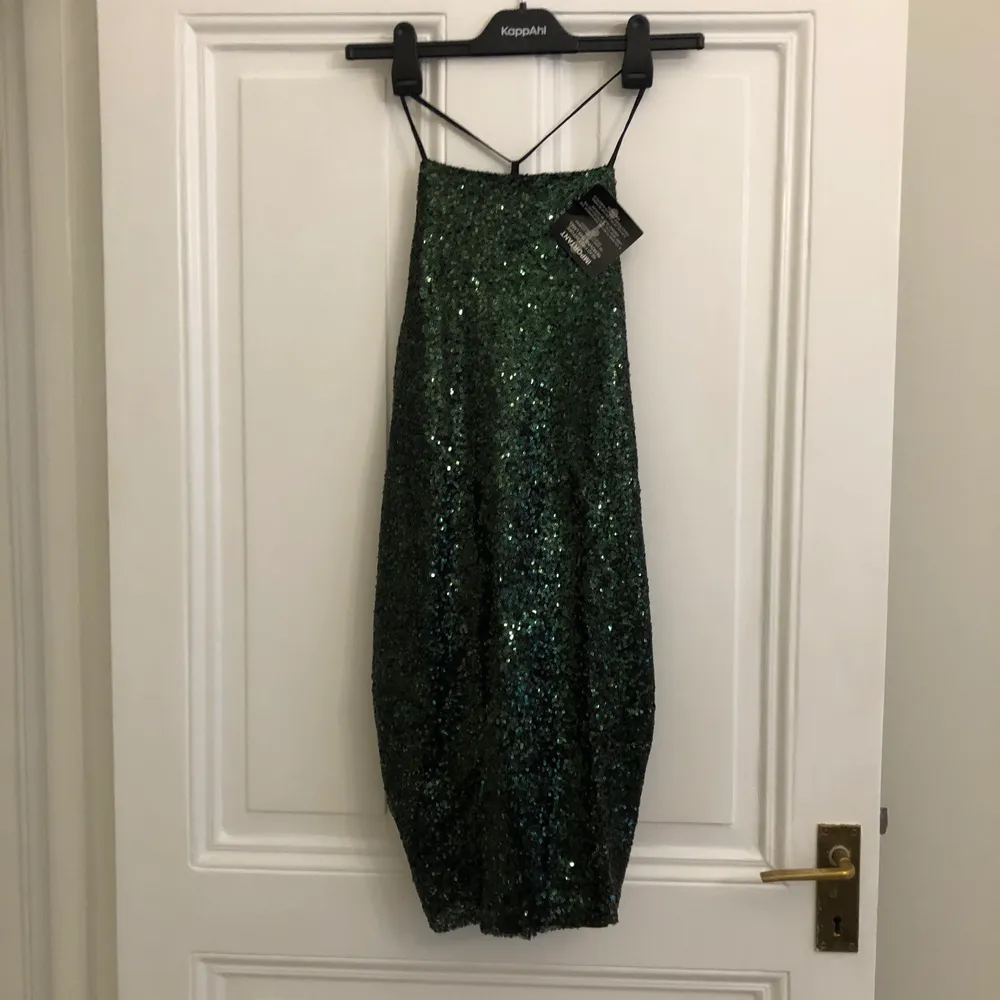 Festlig grön paljettklänning med djup öppen rygg från Rebecca Stella x Nelly strl XS. Oanvänd och fint skick!. Klänningar.