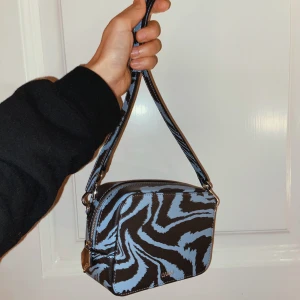 Ganni väska i skinn - Axelremsväska från Ganni i mönstrat skinn. Köpt förra året och endast använd en gång. Superfint skick men säljer då den inte kommer till användning 💙