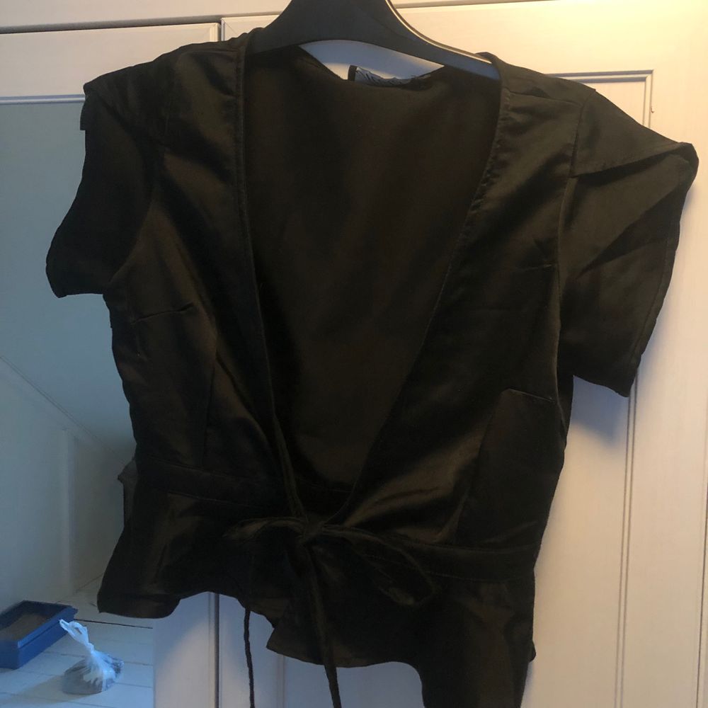 Topp i sidentyg från Motel. Väldigt urringad och sexig! Man knyter toppen med två band. Volang nedtill. Kortare modell. Tyget är väldigt tunt och har blivit lite ”repigt”, som små skåror i. Det syns knappt när man bär den dock 🤗 Obs! Katt finns i hemmet 🥰. Toppar.