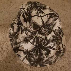 Buckethat - En buckethat som man kan vända ut och in på! På ena sidan är den svart och på andra sidan är den vit med palmer.🖤🗯🏝