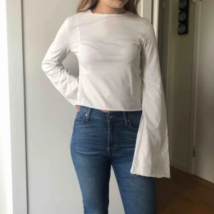  - En långärmad benvit crop-top från Urban Outfitters med utsvängda ärmar