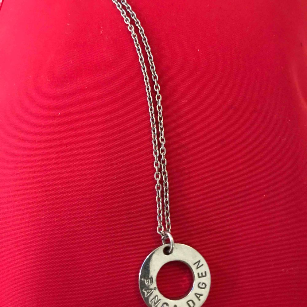 Silverfärgat halssmycke med budskapsring med text,