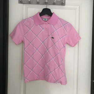  - En rosa piké från Lacoste. Köpt på second hand. Den har ett litet hål på sömmen i bak.   Jag kan mötas upp i Mariestad, annars står jag för frakten.