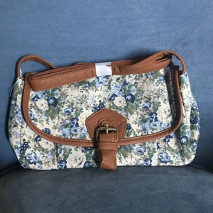  - Söt, blommig axelremsväska, kantad av bruna detaljer. Perfekt mellanstorlek. Aldrig använd. Frakt ingår i priset! 