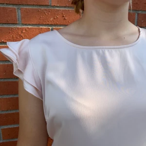 Ljusrosa klänning volanger  - Klänning är i ett silkigt material, den slutar strax över knäna och har resår i midjan. Volang armarna ger en fin form i klänningen. Använd på en skolavslutningen. Du står för frakten:)