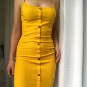 Ribbad klänning - Ribbad långklänning med slits och knappar. Färgen är orange/mörkare gul. Mycket fint skick, knappt använd.