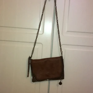 Fejk-Stella McCartney - En fejk Stella McCartney-crossbody i ljusbrun färg mot det guldiga hållet köpt i Turkiet. Bra skick.
