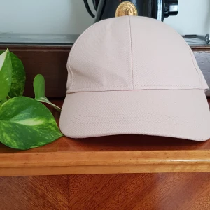 Ljusrosa keps, h&m - Ljusrosa tygkeps från h&m divided. One size - justerbart spänne bak. 100% bomull. Något gråaktig på skärmen (se bild), men i princip oanvänd. Frakt tillkommer.