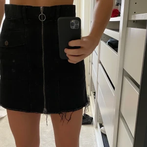 Svart jeanskjol med dragkedja  - Svart jeanskjol med dragkedja från bershka. Fickor fram & dragkedjan går att dra hela vägen. Fransig längst ner super snygg & trendig passar till allt tjocktröjor samt sommartoppar